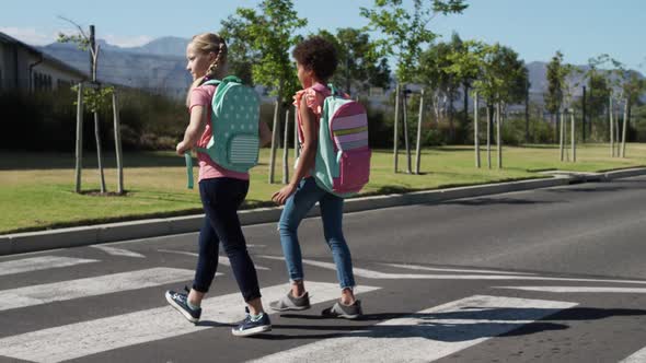 Two girls with school bags crossing the road