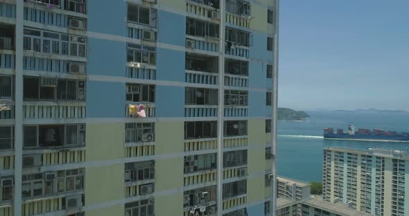 The Drone Rises Along the Facade of an Apartment Building with Cargo Ship on Background