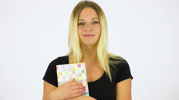 A Young Beautiful Woman Holds a Book and Smiles at the Camera - White Screen Studio