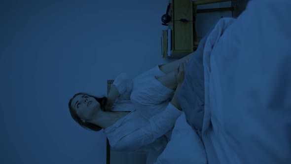 Upset Woman Sits on Bed at Late Dark Night Kneading Neck