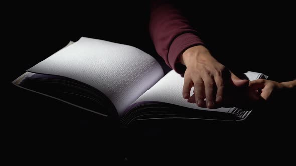 Man Reading a Book for the Blind in a Dark Room . Close Up alt