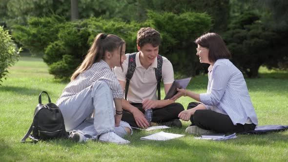 School Teacher Psychologist Social Worker Talking to Teenagers Sitting on Grass