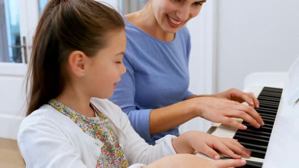 Mother assisting daughter in playing piano 4k