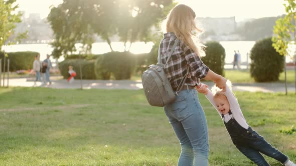 Mother and Little Daughter Are Having Fun in the Park in Sunny Weather