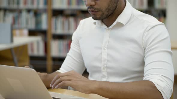 Focused African American Professor Typing on Laptop at Library