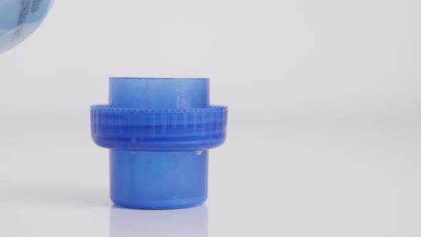 Fabric softener container cap being filled on white  slow-mo footage