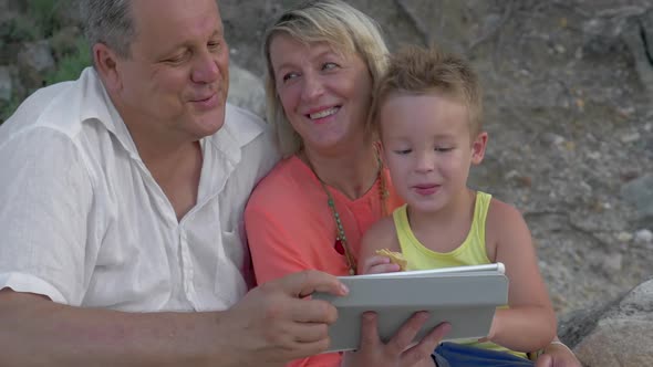 Mother,father and Son Watching Video on Pad While Sitting on Beach