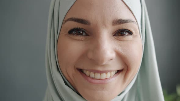 Closeup Portrait of Cheerful Young Muslimah in Hijab Smiling Looking at Camera Indoors at Home