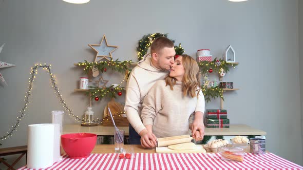 Pregnant Woman with Husband in New Year Kitchen Roll Out Dough with Rolling Pin