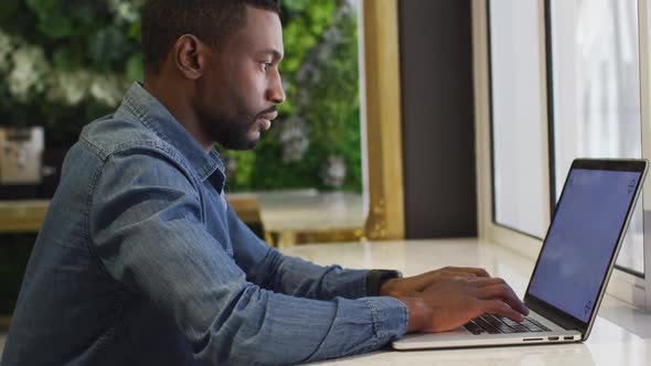 African american businessman using laptop in modern cafe