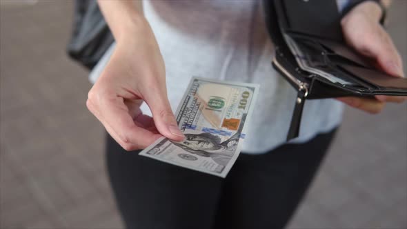 Top View a Bill of 100 Dollars in a Woman's Hand the Girl Takes Out a Banknote From Her Wallet and