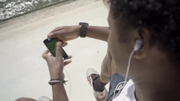 African American Young Man with Digital Devices on Embankment