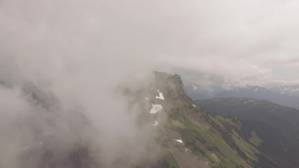 Clouds slowly reveal a distant mountain peak.