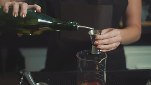 Mixologist measures liquor with jigger for mixed drink, close up slider.