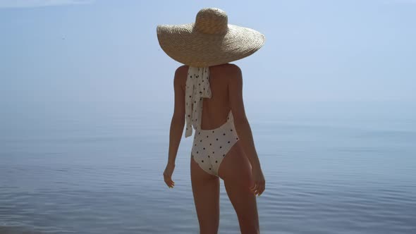 Relaxed Girl Standing Beach Raising Hands to Brimmed Hat Close Up