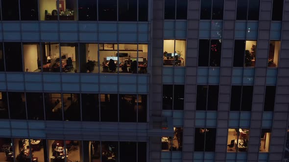 Rising Tilt Down Footage of Lighted Windows in Tall Business Building in City