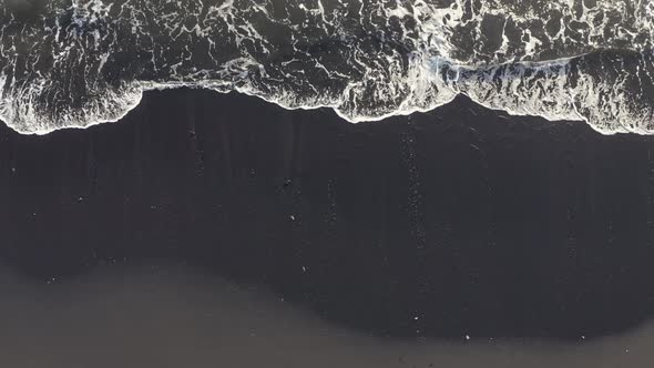 Aerial View Powerful Ocean Waves at Black Volcanic Beach Crashing and Foaming.