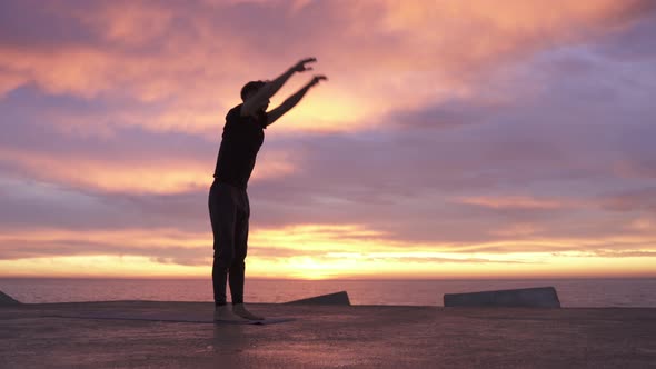 Young Athletic Man Performing Yoga Pose in Front of the Ocean at Sunrise