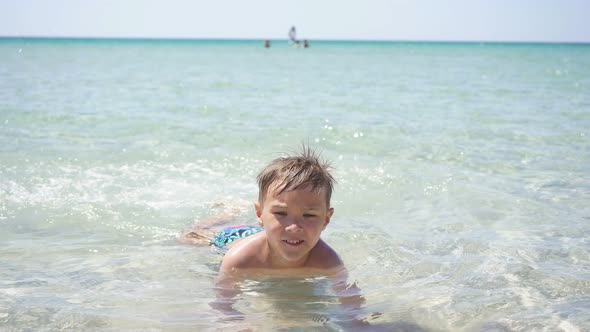 Cute Boy Learn To Swim in the Crystal Clear Sea in Shallow Water