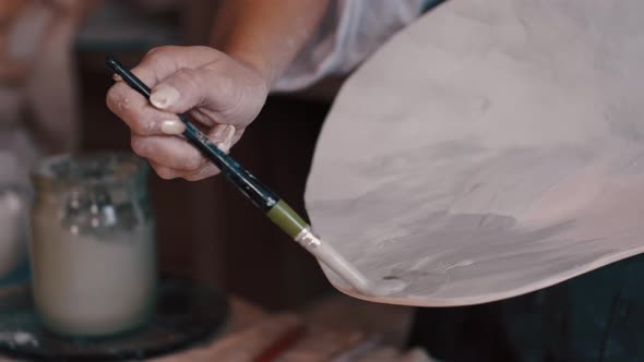 Professional Potter Decorating and Painting a Dish After She Has Baked It in the Kiln