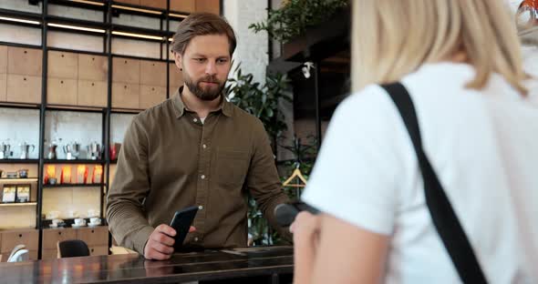 Young Man is Buying Takeaway Coffe in Coffeeshop and Paying with Smartphone Making Contactless