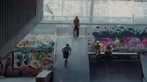 Sporty Teenage Riders Practicing Together on Scooter and Bmx Bike at Skatepark