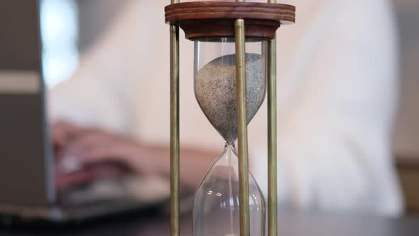 Woman Working Behind a Laptop Out of Focus Focus on the Hourglass