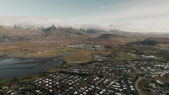 Slow aerial tilt up above Reykjavik, Iceland. Snow-capped mountain range in background.