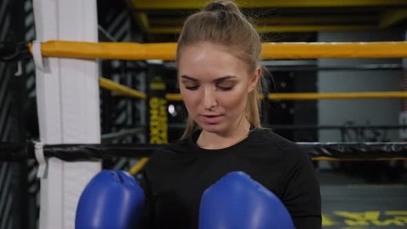 Portrait of a Young Woman in Sportswear and Boxing Gloves in the Gym