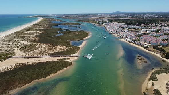 Boats Cruising Across Turquoise River In Cabanas de Tavira In Algarve, Portugal On A Sunny Day. aeri