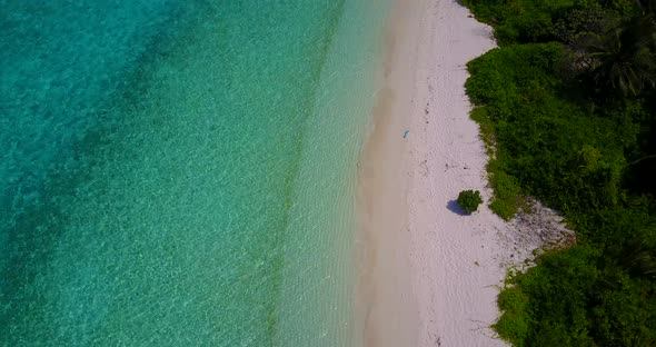 Wide angle overhead clean view of a sunshine white sandy paradise beach and aqua turquoise water bac