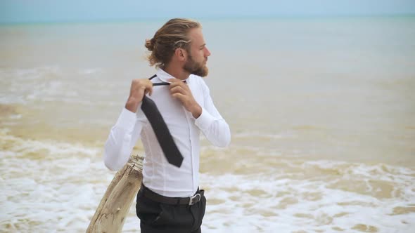Blond Haired Young Businessman Loosening Tie and Throwing It Out Near Seaside in Slow Motion
