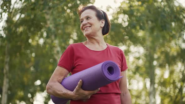 Elderly Woman with Yoga Mat in Her Hands