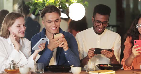 Young Good Looking People Using Their Smartphones and Smiling While Spending Time Together. Crop