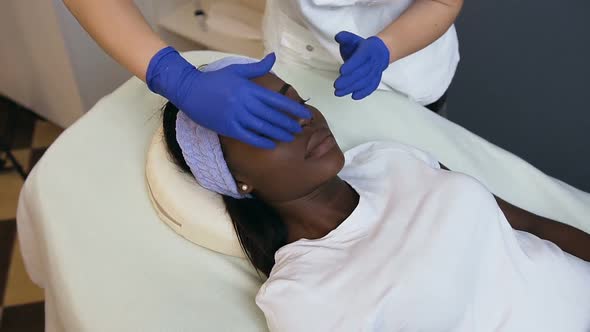 Cosmetologist Making Relaxing Massage to the Female African Client