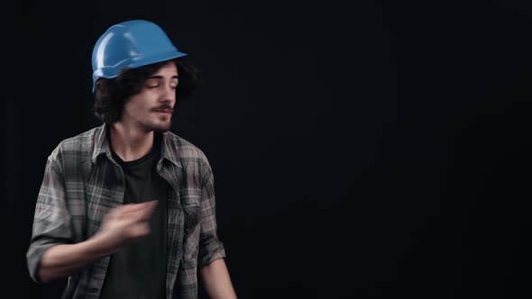 The Charismatic Boy in the Blue Helmet of the Engineer Points His Finger to One Side Looks