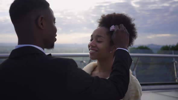 Portrait of Smiling Happy African American Bride Looking with Love at Groom Putting Flower in Hair