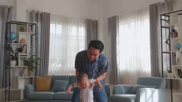 Young Asian Father And Little Son. A Man Throws Up A Toddler At Home