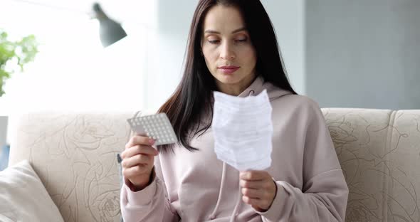 Woman Holds Blister Pack of Pills in Hands and Reads Medical Instructions