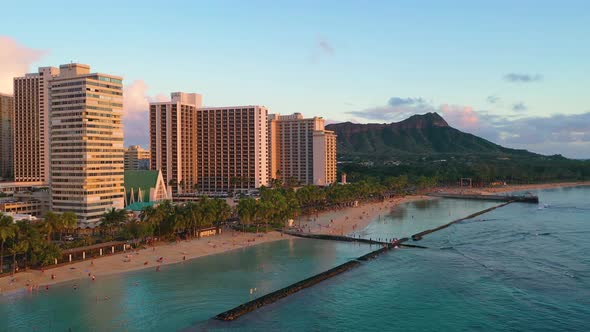 Drone Flyover Crowded Hawaiian Beach with People Relaxing in Sand And Diamond Head Tuff Cone Overloo