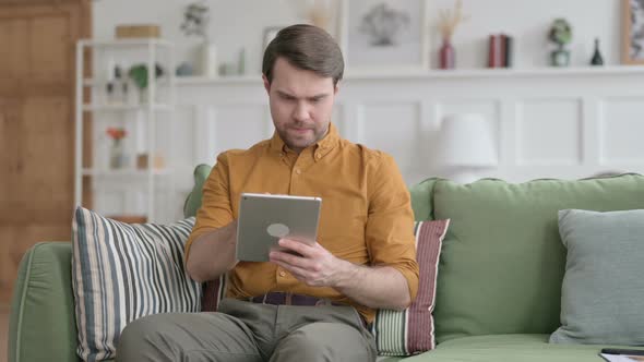 Young Man using Tablet on Sofa