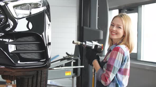 Blond Girl Screwing Car Wheel at the Garage