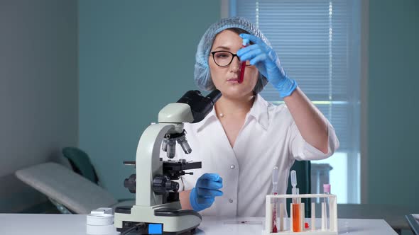 Lab Assistant Shakes Test Tube with Red Liquid in Hospital