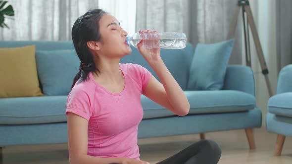 Young Asian Woman Drinking Water And Resting, Having Break After Doing Exercise At Home
