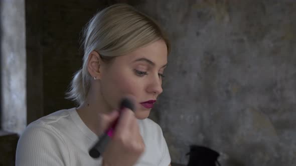 Woman makes makeup. Young woman makes blush on the face using makeup brush