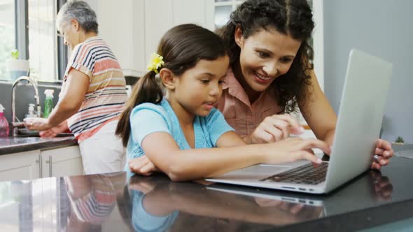 Mother and daughter using laptop in kitchen 4k