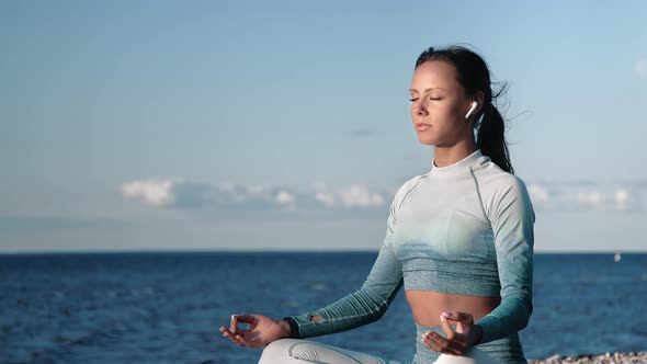 Tanned Fitness Woman Practicing Yoga Meditating with Closed Eyes on Sunset Beach Sea Sky Coast