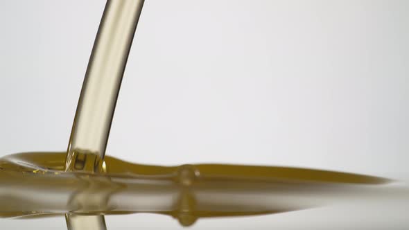 Golden oil pouring against white background. Slow Motion. Unedited version included.