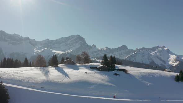 Drone flying towards cabins on a beautiful snowcovered landscape