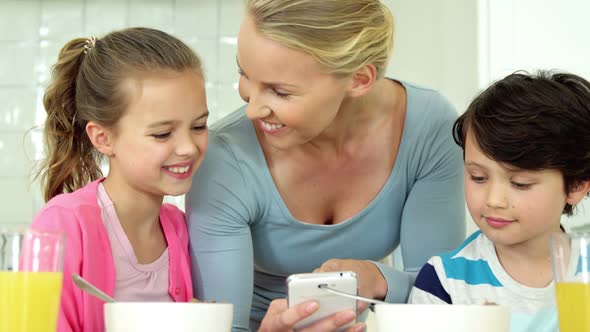 Family using mobile phone while having breakfast